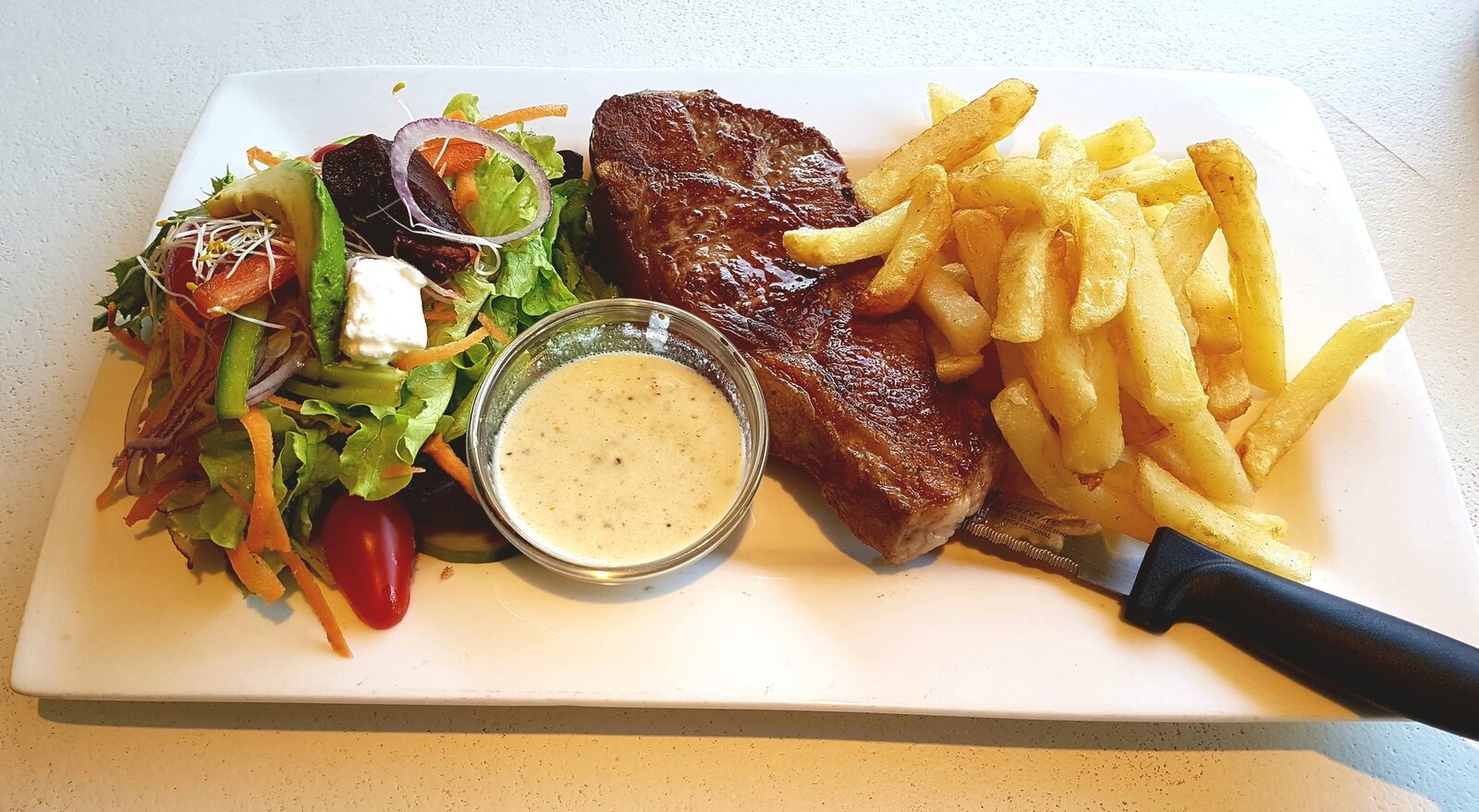 Steak and chips served with salad and sauce
